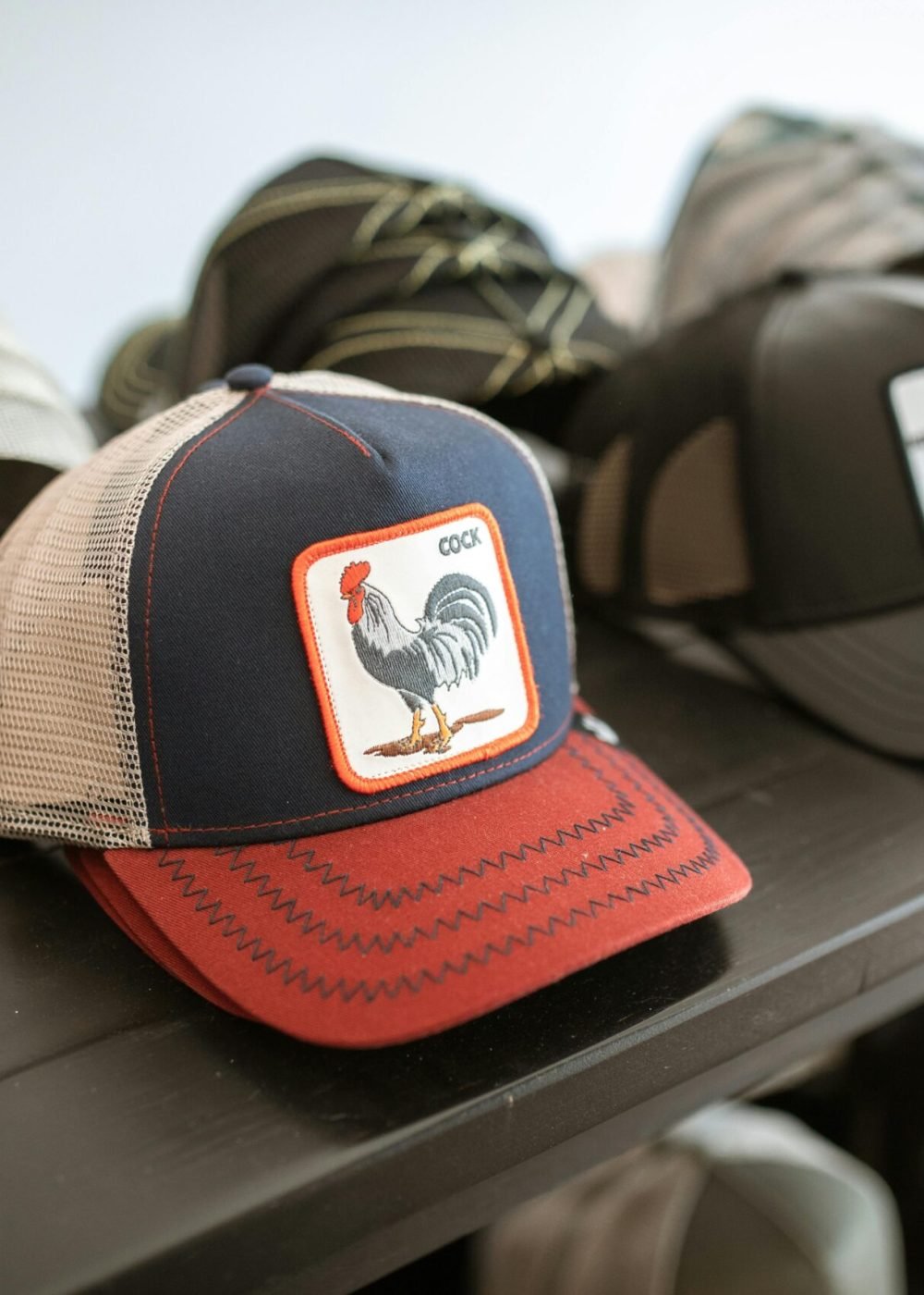 Collection of fashionable graphic caps displayed on a shelf, highlighting unique rooster design.